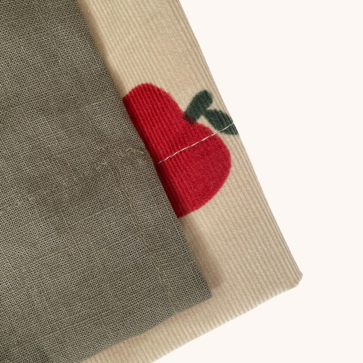 Materialdetail von Dirndl Polly mit rotem Apfelmotiv und graugrünem Leinenstoff